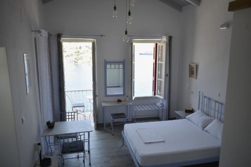 a bedroom with a bed and a table and two windows at Marea Apartments in Symi