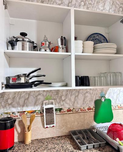 a kitchen with white shelves with dishes and utensils at Casa central in Tetouan