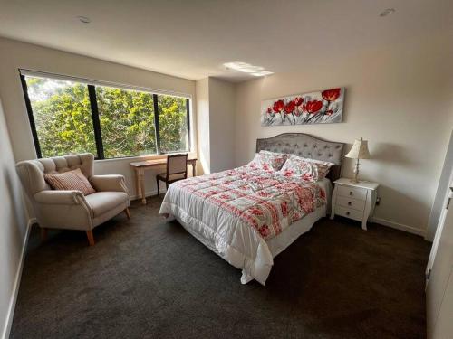 a bedroom with a bed and a chair and a window at Brand New & Central - 3 Bedrooms with 3 En suites in Auckland