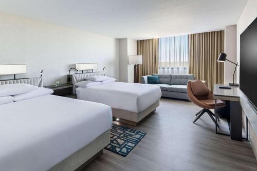 a hotel room with two beds and a couch at Hyatt Regency O'Hare Chicago in Rosemont