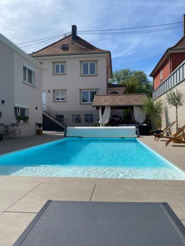 une grande piscine bleue devant une maison dans l'établissement Les petites plumes d’Hag, à Haguenau