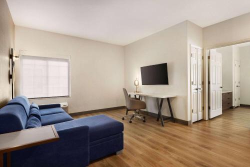 a living room with a blue couch and a desk at La Quinta by Wyndham Port Arthur in Port Arthur
