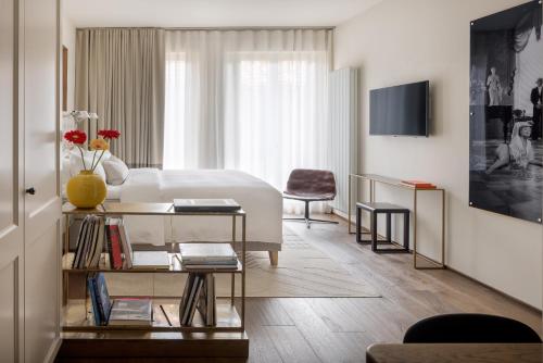 Porta Nera Private Living - adults only في فلورنسا: غرفة نوم بيضاء مع سرير وطاولة مع كتب