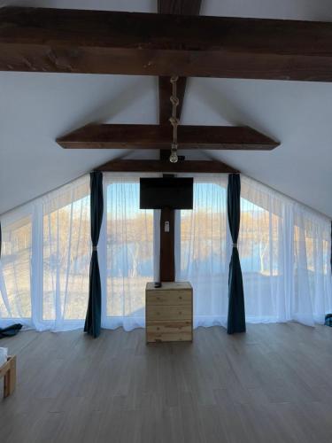 a living room with a tv and curtains at Casa de la Baltă in Rieni