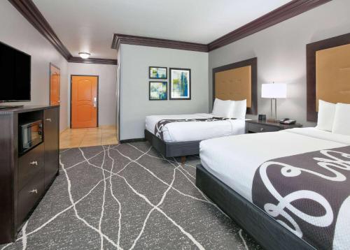 a hotel room with two beds and a flat screen tv at La Quinta by Wyndham Little Rock - Bryant in Bryant