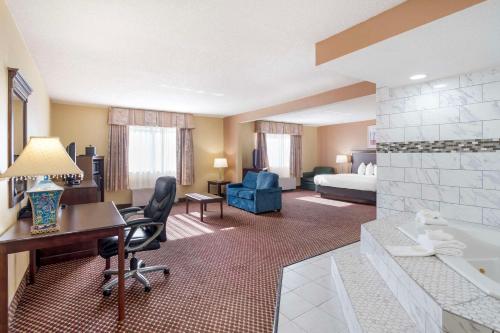 a hotel room with a bed and a desk and a room at Quality Inn & Suites Bloomington University Area in Bloomington