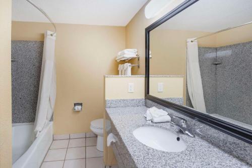 a bathroom with a sink and a toilet and a mirror at Quality Inn & Suites Bloomington University Area in Bloomington