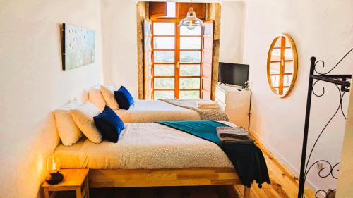 een slaapkamer met 2 bedden en een raam bij Lagarto Pintado Casa n'Aldeia in Castelo Novo