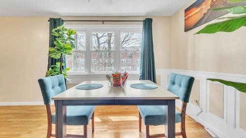 a dining room table with blue chairs and a window at Central Chic Crib in Manchester