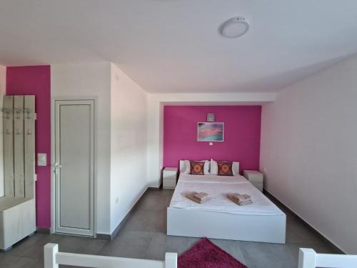a bedroom with a pink accent wall and a bed at Flamingo Resort in Belgrade