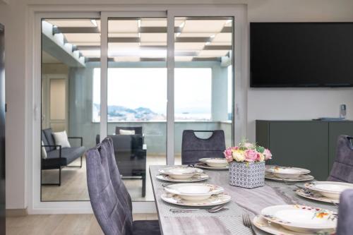 a dining room with a table and chairs and a television at Apartman Palma and Luxury Penthouse for a family with swiming pool,parking,terrace,panoramic view at the sea,Podstrana in Podstrana