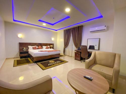 a bedroom with a bed and a desk and a table at Aveon Hotel in Abuja