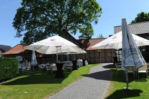 dos sombrillas blancas, mesas y sillas en el césped en Kaiserhof en Willich