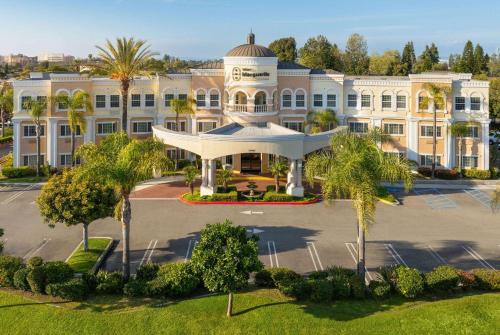 an aerial view of a large building with palm trees at Hotel Marguerite South Anaheim - Garden Grove, Trademark Collection by Wyndham in Anaheim
