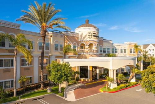 an exterior view of a building with a palm tree at Hotel Marguerite South Anaheim - Garden Grove, Trademark Collection by Wyndham in Anaheim