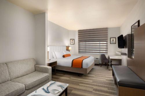 um quarto de hotel com uma cama e um sofá em Hotel Marguerite South Anaheim - Garden Grove, Trademark Collection by Wyndham em Anaheim