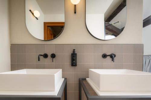 two sinks in a bathroom with two mirrors at 1448 Antica Dimora Al Merlo Bianco in Cividale del Friuli