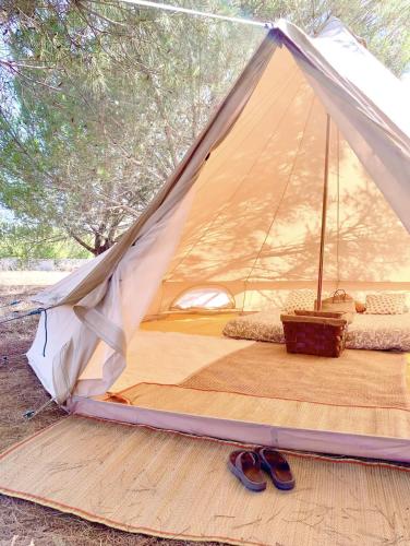 a tent with a bed and a pair of shoes at Glamping with Yoga and Natural Pool near Fuseta Beach in Moncarapacho