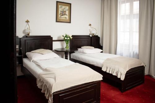 a room with two beds and a table in it at Hotel Dwór Polski in Wrocław