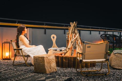 a woman sitting in a chair next to a fireplace at THALAY Cha-am by THA in Cha Am