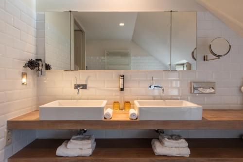 La salle de bains est pourvue de 2 lavabos et d'un grand miroir. dans l'établissement Hotel De Barrier, à Aan de Wolfsberg