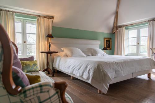 ein Schlafzimmer mit einem weißen Bett und einem Stuhl in der Unterkunft Hotel De Barrier in Aan de Wolfsberg