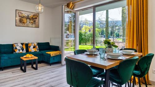 a dining room with a table and chairs and a couch at Apartamenty z basenem i saunami STONE HILL RESORT II VIP Centrum by Royal Aparts in Szklarska Poręba