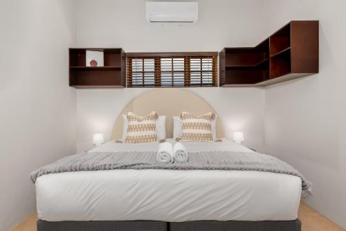 a bedroom with a white bed with two slippers on it at Agapanthus 8 in Cape Town