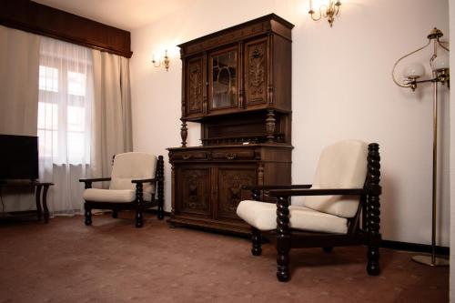 a room with two chairs and a large wooden cabinet at Hotel Dwór Polski in Wrocław