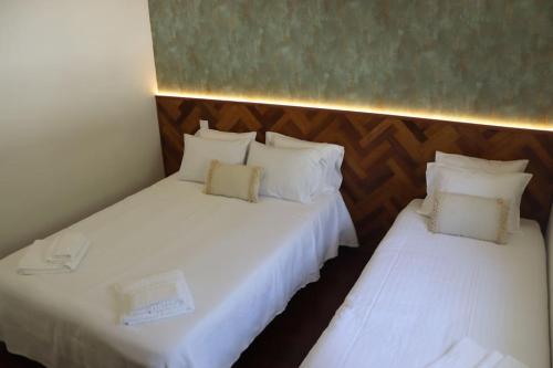 two beds in a room with white sheets and pillows at Alieira's House - Pet Friendly in Torres Novas