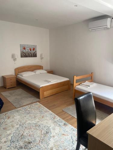 a bedroom with two beds and a table and a chair at Apartments & Rooms L E F T RIVER Belgrade in Belgrade