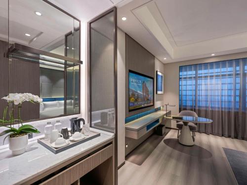 a bathroom with a sink and a table and a tv at Novotel Kunshan Yangcheng Lake in Kunshan