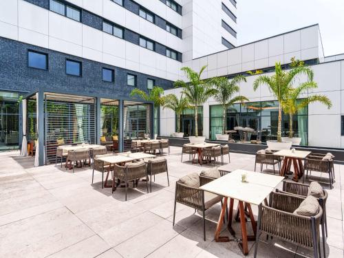 un patio al aire libre con mesas y sillas y un edificio en Mövenpick Hotel Abidjan, en Abiyán