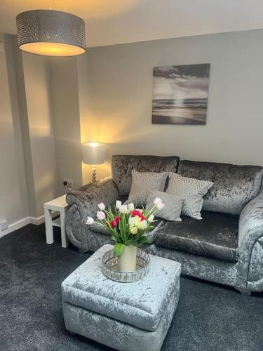 a living room with a couch and a table with flowers at Studio 61 fremington near instow in Fremington
