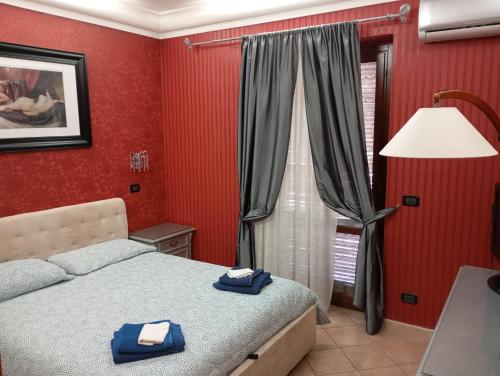 una camera da letto con pareti rosse e un letto con asciugamani blu di Enza-home-in-ROMA a Borghesiana