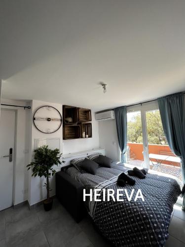 une chambre avec un lit et une horloge au mur dans l'établissement T2 HEIREVA Résidence Les hameaux de saint-cyprien LECCI, à Porto-Vecchio