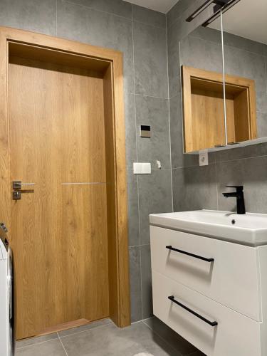 uma casa de banho com um lavatório e uma porta de madeira em Apartmán Thermal Park 