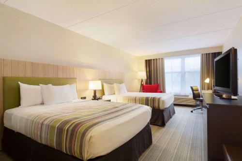 a hotel room with two beds and a flat screen tv at Country Inn & Suites by Radisson, Madison Southwest, WI in Fitchburg