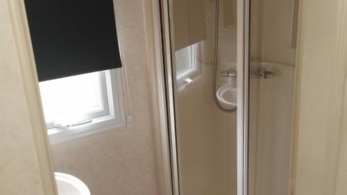 uma casa de banho com um chuveiro, um WC e uma janela. em 3-Bed 8 berth static caravan in ingoldmells em Skegness