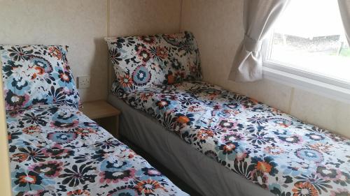 uma cama num pequeno quarto com uma colcha florida em 3-Bed 8 berth static caravan in ingoldmells em Skegness