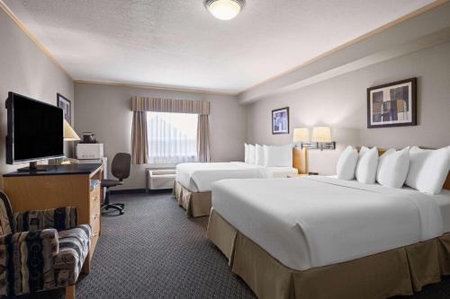 a hotel room with two beds and a flat screen tv at Travelodge by Wyndham Fort McMurray in Fort McMurray