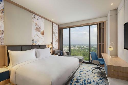 Habitación de hotel con cama, escritorio y ventana grande. en Doubletree By Hilton Jakarta Bintaro Jaya en Serpong