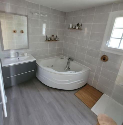 une salle de bain blanche avec une baignoire et un lavabo dans l'établissement Belle villa, avec Jardin Piscine Jacuzzi et Sauna, à Istres