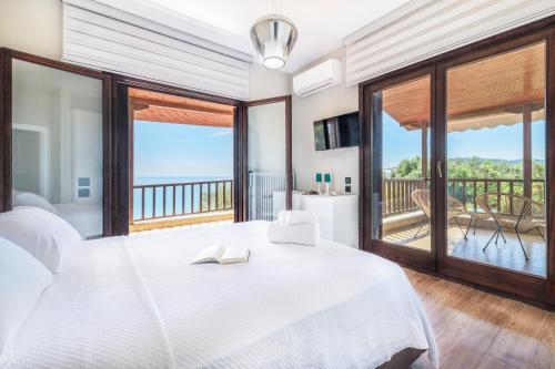 a bedroom with a large white bed and a balcony at Iconic PRIVE beachfront villa Mola Kaliva in Mola Kalyva