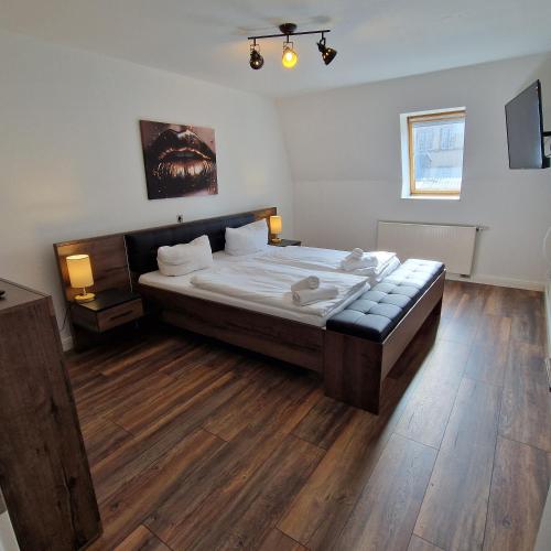 sypialnia z dużym łóżkiem i drewnianą podłogą w obiekcie DM Hotes & Apartments - Apartment Dosborn 2A w mieście Dingelstädt