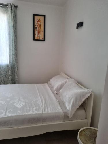 a bed with white sheets and a picture on the wall at villa avec piscine in Somone