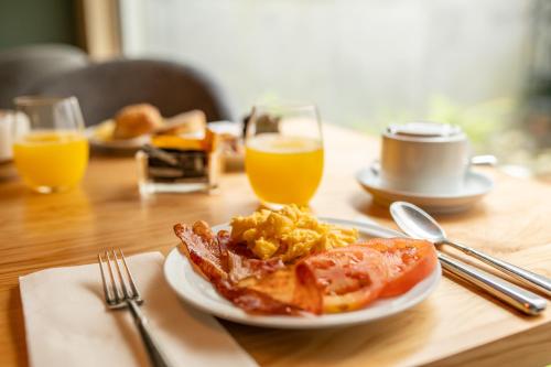 a plate of breakfast food on a table with orange juice at ANC Resort in Caloura