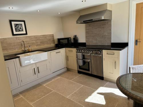 a kitchen with white cabinets and a sink and a stove at Bank Top Barn Cosy Self Catering 4 Guests in Pickering
