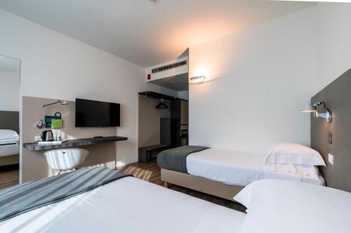 a hotel room with two beds and a tv at Airport Hotel Bergamo in Bagnatica