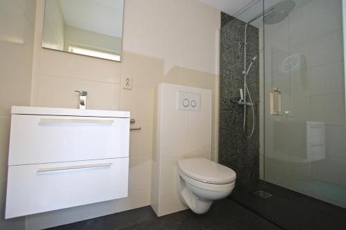 a white bathroom with a toilet and a shower at Studio Eb in Egmond aan Zee